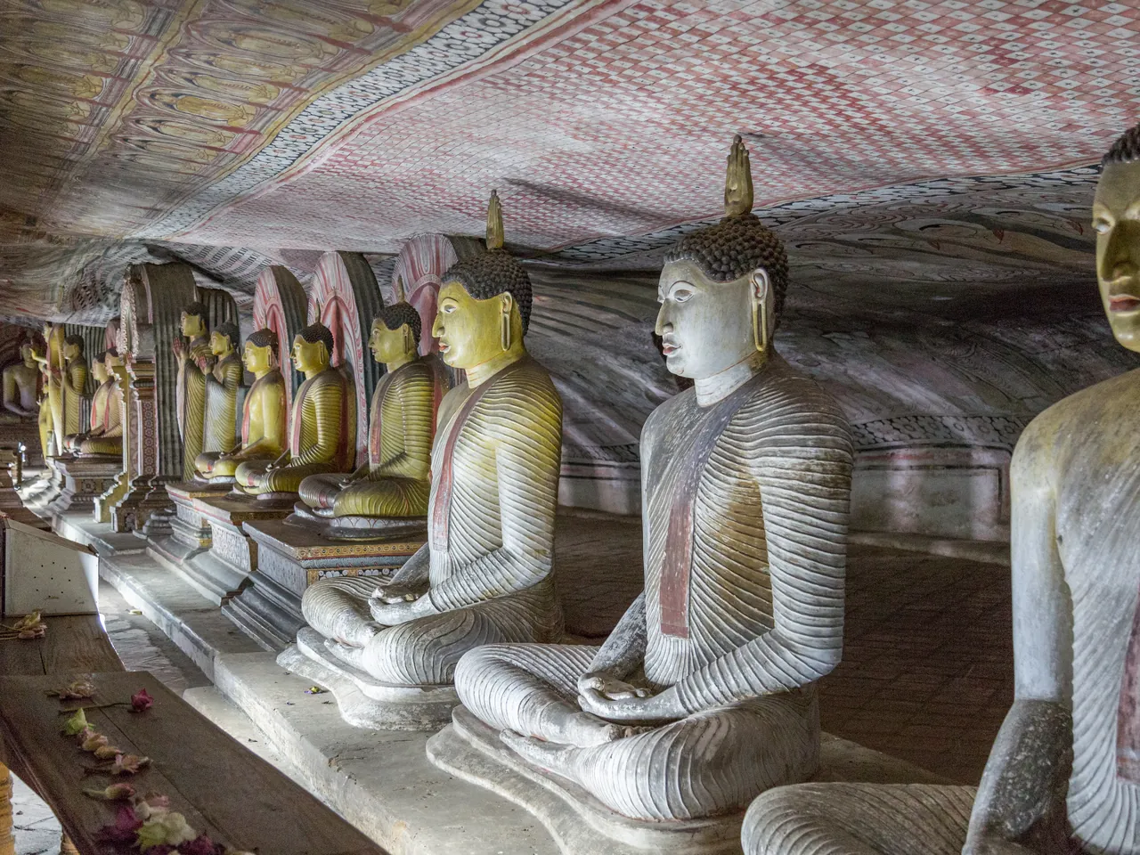 Eine Reihe sitzender Buddha-Statuen im historischen Höhlentempel von Dambulla in Sri Lanka.
