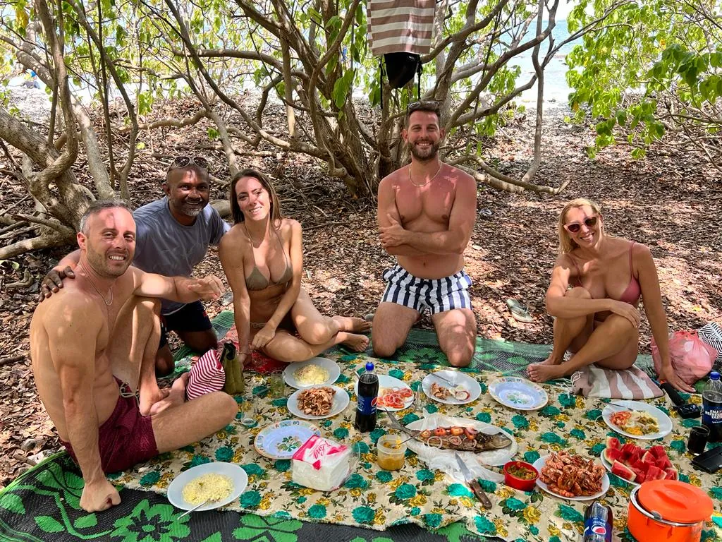 Reiseleiter Romesh mit Gästen bei einem Strandpicknick mit frischem Fisch während einer Rundreise durch Sri Lanka.